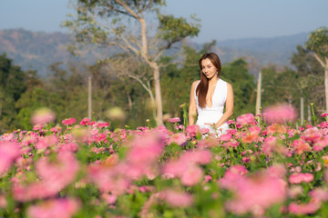 happy young woman enjoying summer in zinnia field. Beautiful woman relaxing in pink flower garden.