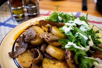 Kebab meat with roasted potatoes and salad on plate