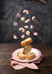 Ingredients of a canape recipe with garlic prawns, in the air, falling to the plate.