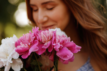 a bouquet of peonies in the background the girl is blurred. artistic effect