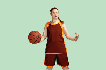 Young caucasian female basketball player in action, motion during gameplay isolated on mint colored...