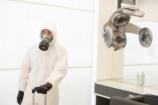 Tecnico per la Sanificazione dei locali e degli ospedali con tuta e maschera protettiva professionale dentro un salone per parrucchieri