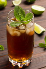 Cold summer tea with ice and mint. On table lime and mint leaves.