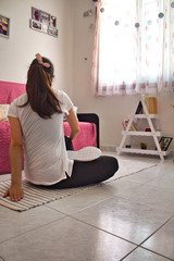 Young woman wearing black leggins and white t-shirt while doing yoga and meditation at home