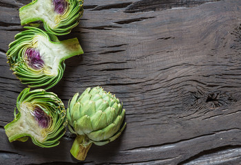 Obraz premium Green and purple artichoke flower edible buds on wooden background.