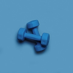 two blue dumbbells on a blue monochrome background