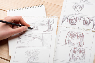 Artist drawing an anime comic book in a studio. Wooden desk, natural light. Creativity and inspiration concept.