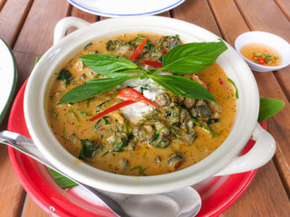 Traditional Thai food, Thai curry with river snail
, betel leaves and climbing wattle in coconut milk, decorated with red chili and basil.
