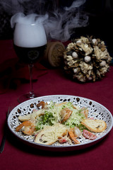 Vegetable salad with bread, shrimp and cheese. Near a glass of wine with smoke, flowers on a red tablecloth