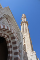 Fototapeta premium A minaret of a mosque staring into the clear blue sky. Beautiful architecture. Stone lace