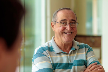 elderly man with glasses smiling, narrow focus