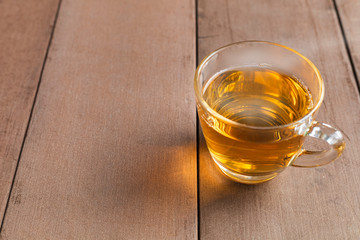 Close up hot tea cup on wood table . hot tea in handle glass with copy space for text or design.