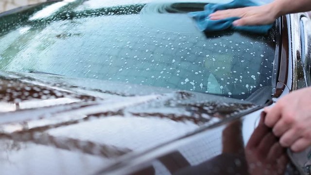 Man carefully wash his car windscreen and roof