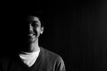 Low key portrait of a smiling young handsome boy in the dark 