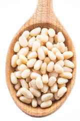 Pine nuts in the wooden spoon. White background.