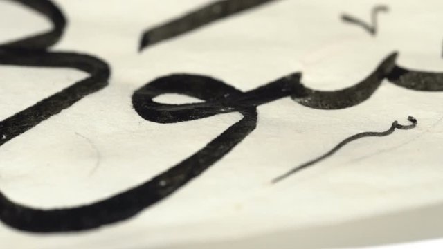 calligrapher writes arabic lettering with calligraphy pen on parchment. macro shot of islamic calligraphy art. close up slider dolly shot