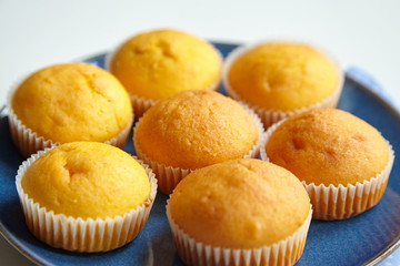 Pumpkin muffins on blue plate on white table with napkins, homemade bakery