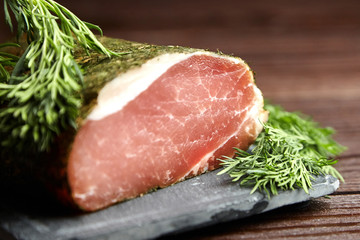 Polendwitz is a jerky tenderloin, dried pork with spices and fresh green dill, slate cutting board on brown table