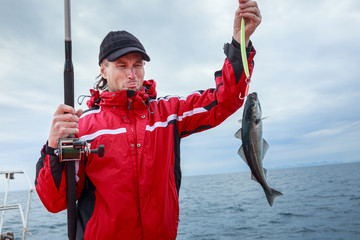 A sailor with a trophy fish caught on the boat in open sea in Norway