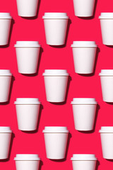 Pattern of disposable coffee cups on a red background. Flat lay.