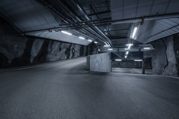 Sci fi looking dark and moody underground parking lot with fluorescent lights on.  Two ways