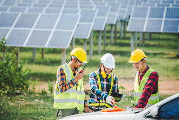 Fototapeta premium A team of engineers and design architects, three Asian men held a design and planning meeting. At the solar power generating station, an Asian engineer team ordered and walked around the solar panel.