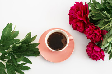 pink cup of coffee and three red peonies on the white background