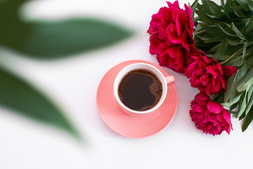 pink cup of coffee and three red peonies on the white background
