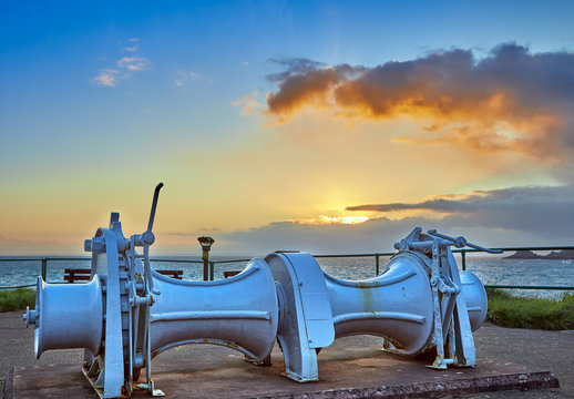 Image of La Mouve Winch at Bouley Bay at sunrise with the sea and headland in the background. Jersey Channel Islands