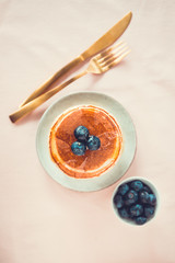 Top view of American traditional pancakes with honey and fresh blueberry.
