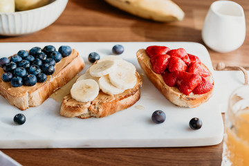 Toasts with peanut butter, blueberry, strawberry and banana. Healthy breakfast concept.