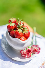 Jug full of starwberries with flower decoration, summer dining in garden