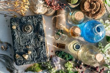 Ancient magic recipe book and magic potions in the bottle on the witch doctor table background.