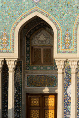 Exterior of mosque facade with white columns and amazing ornamental tiles decorating wall, Iran.