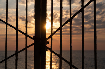 Sea sunset behind the fence grill