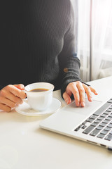 girl sits at a table, near a computer and a coffee mug