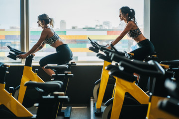 Fototapeta na wymiar two girls practicing spinning in modern gym next to a backlit window