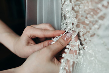 Women's fingers fasten wedding dress clasp close-up nails