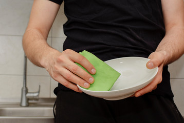 man washes dishes in the kitchen under the tap close up