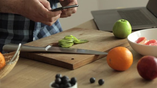 Male hands taking photo of kiwi slices using mobile phone 