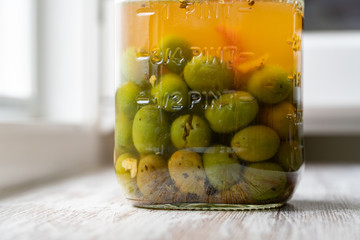 Marinated olives with spices in glass jar on a wooden table.