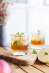 apple juice in glass with ice and mint. Wooden table with refreshment beverages with mint and ice