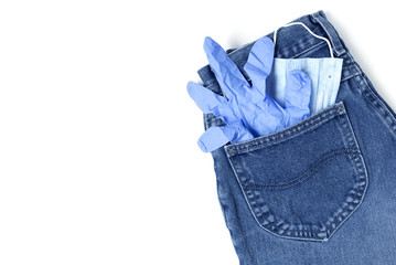 Classic blue jeans on the white background. Medical mask and gloves in the pocket. Pandemic concept. Copy space. Place for text and design. Top view. Flat layout