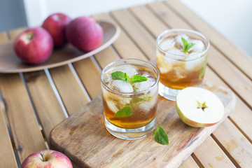 Fresh raw apple juice with ice in glass at wood