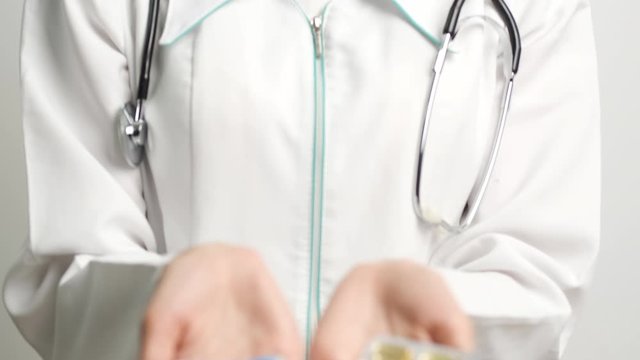 Female doctor holding treatment pills in front of the camera
