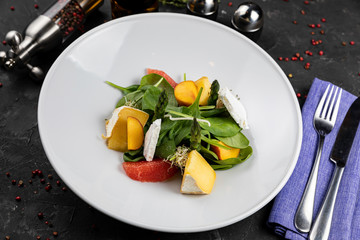 Green salad with cheese and grapefruit on a dark background