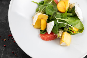 Green salad with cheese and grapefruit on a dark background