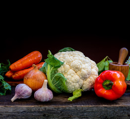 Vegetables - cauliflower carrots garlic onions on a wooden rustic table.