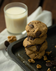 oatmeal cookies with peanut butter and chocolate sparks and a glass of milk on a rusty metal baking sheet