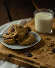 oatmeal cookies with peanut butter and chocolate sparks with a glass of milk on a wooden board